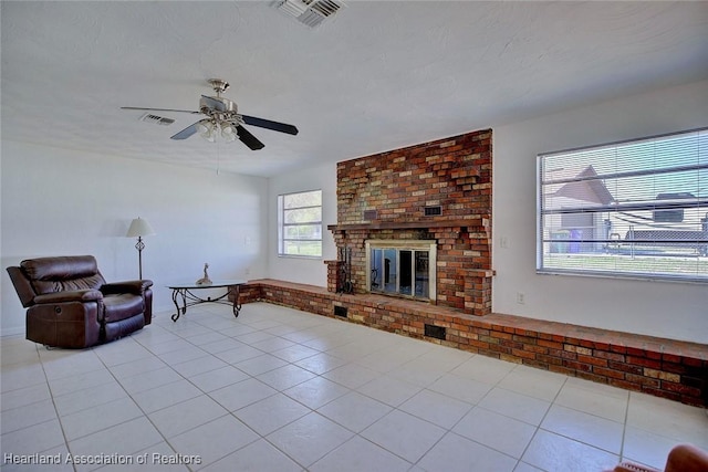 tiled living room featuring a brick fireplace, visible vents, and a textured ceiling