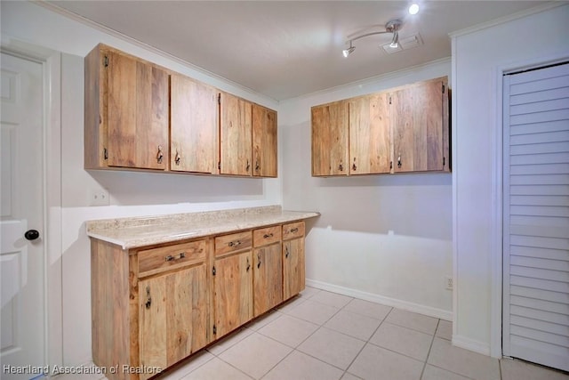 kitchen with light tile patterned floors, visible vents, baseboards, light countertops, and crown molding