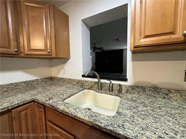 1341 Lake Clay Dr, Lake Placid, FL 33852 - kitchen with a sink, light stone counters, brown cabinets, and a ceiling fan