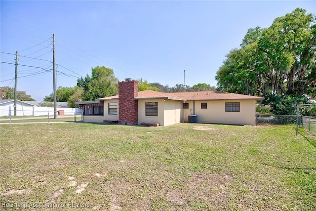 back of property with a lawn, a chimney, fence, and cooling unit