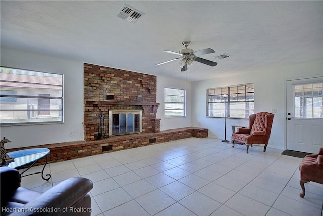 living area featuring a healthy amount of sunlight, a brick fireplace, visible vents, and light tile patterned flooring