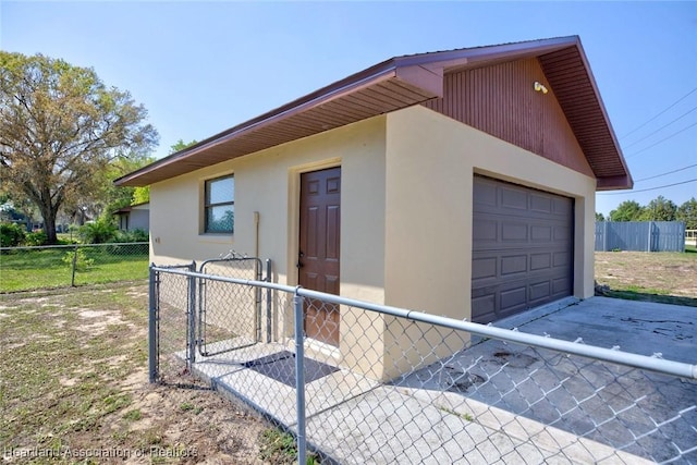 view of side of home featuring an outdoor structure, fence, a gate, and stucco siding