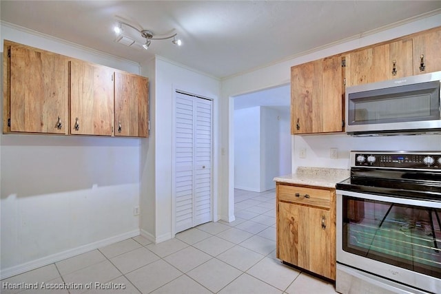 kitchen featuring appliances with stainless steel finishes, light countertops, crown molding, and light tile patterned floors