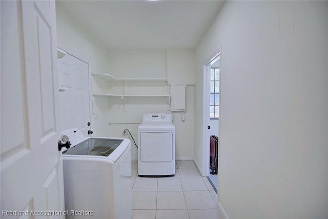 laundry area featuring light tile patterned floors, laundry area, washing machine and clothes dryer, and baseboards