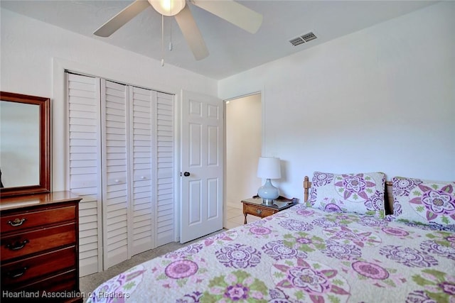 carpeted bedroom with a ceiling fan, visible vents, and a closet