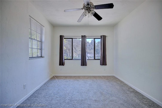 carpeted empty room featuring ceiling fan, plenty of natural light, and baseboards