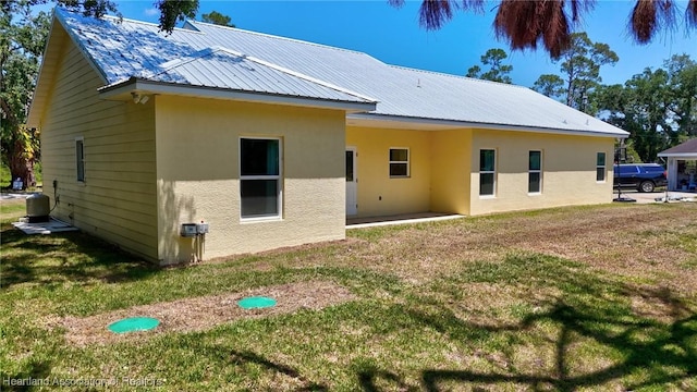 back of property with metal roof, stucco siding, and a lawn