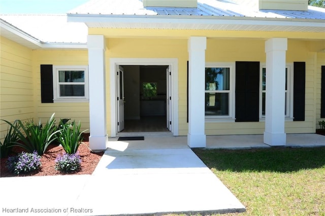 view of exterior entry featuring a porch and metal roof