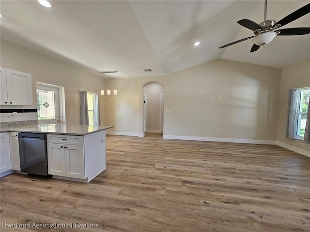 kitchen featuring arched walkways, open floor plan, dishwashing machine, and white cabinetry