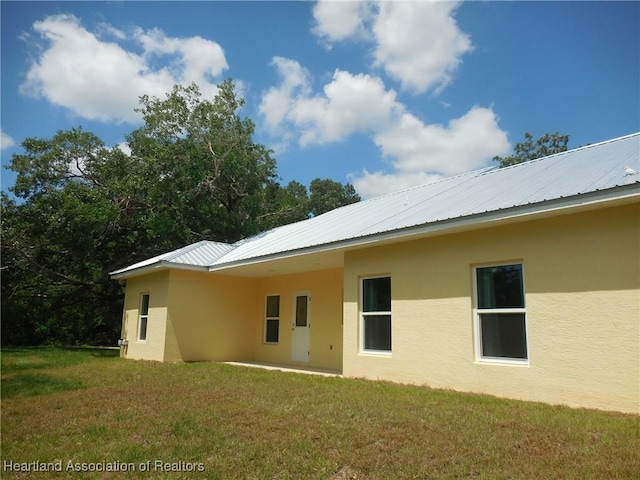 back of house with a yard, a patio, and stucco siding