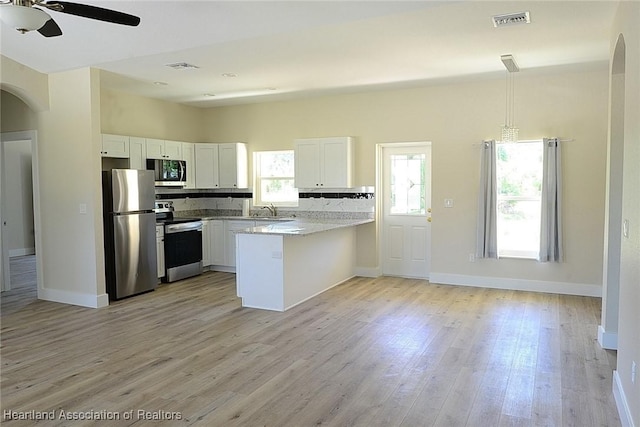 kitchen featuring arched walkways, a peninsula, a ceiling fan, visible vents, and stainless steel appliances