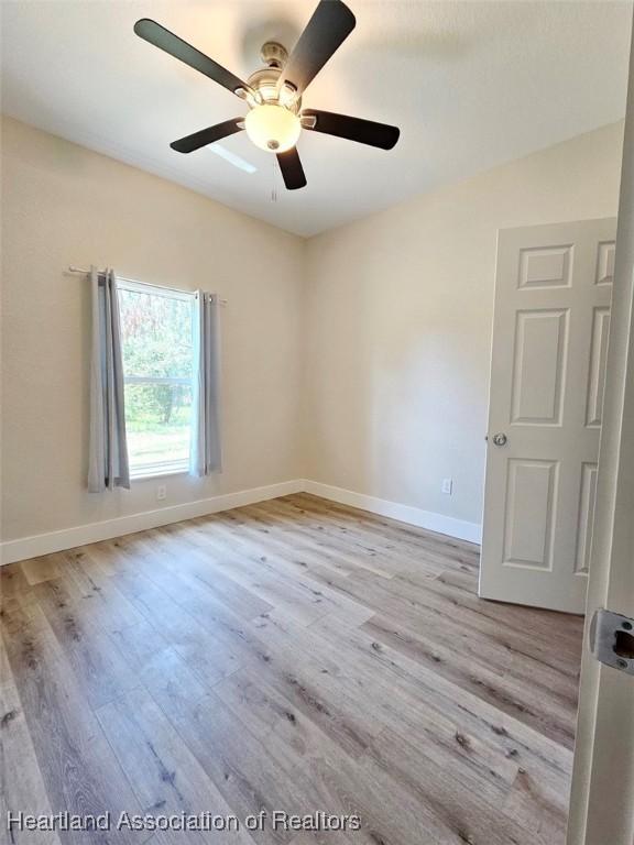 unfurnished room featuring light wood-type flooring, ceiling fan, and baseboards