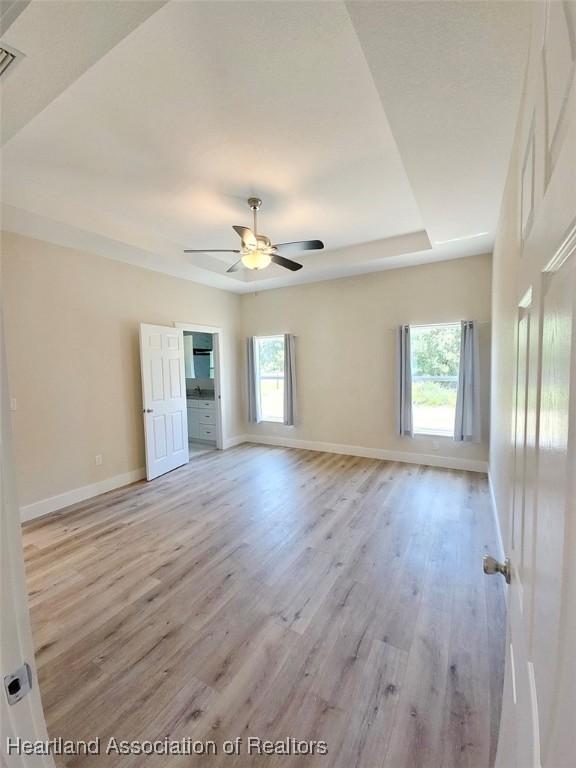 empty room with light wood-type flooring, baseboards, and a ceiling fan