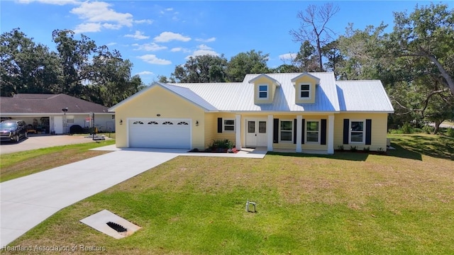 new england style home featuring an attached garage, concrete driveway, a front yard, and metal roof