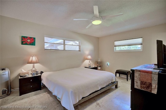 bedroom featuring multiple windows, ceiling fan, and a textured ceiling