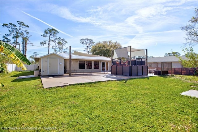 rear view of property with a storage shed, a lawn, a patio, an outbuilding, and fence