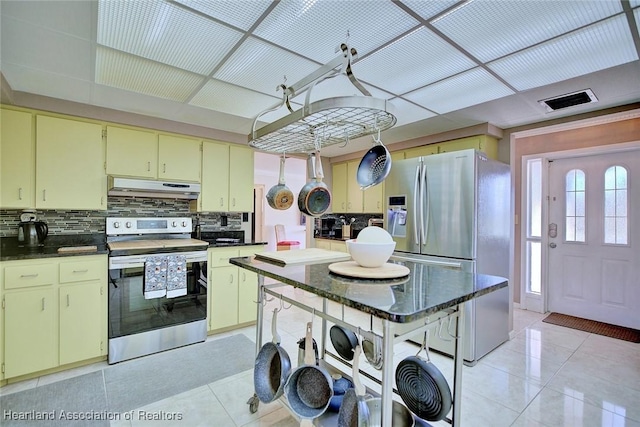 kitchen featuring light tile patterned floors, under cabinet range hood, visible vents, appliances with stainless steel finishes, and decorative backsplash