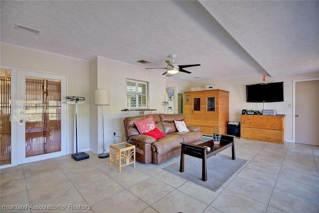 living area featuring light tile patterned floors, visible vents, ornamental molding, a ceiling fan, and a textured ceiling