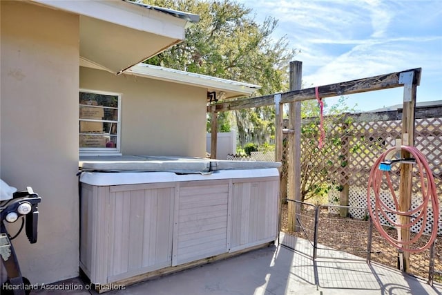 view of patio / terrace with fence and a hot tub