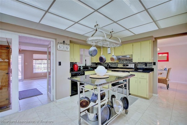 kitchen featuring light tile patterned floors, dishwashing machine, under cabinet range hood, stainless steel electric range oven, and dark countertops