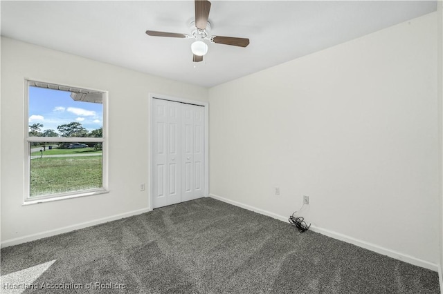 unfurnished bedroom with dark colored carpet, ceiling fan, and a closet