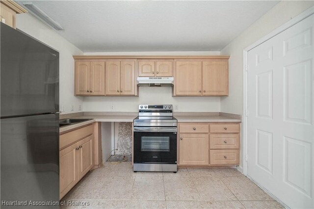 kitchen with stainless steel electric stove, black refrigerator, light tile patterned flooring, and light brown cabinetry