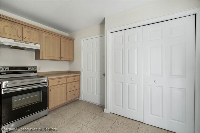 kitchen featuring light tile patterned floors, stainless steel range with electric stovetop, and light brown cabinetry