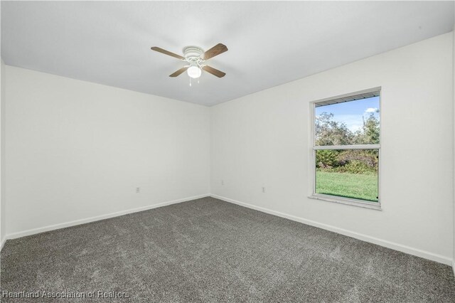 spare room with ceiling fan and dark colored carpet