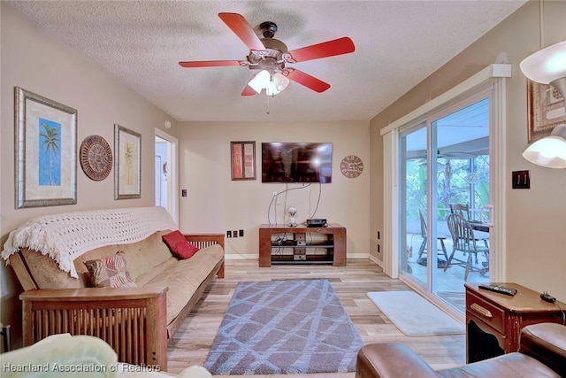 living area with light wood-style flooring, baseboards, ceiling fan, and a textured ceiling