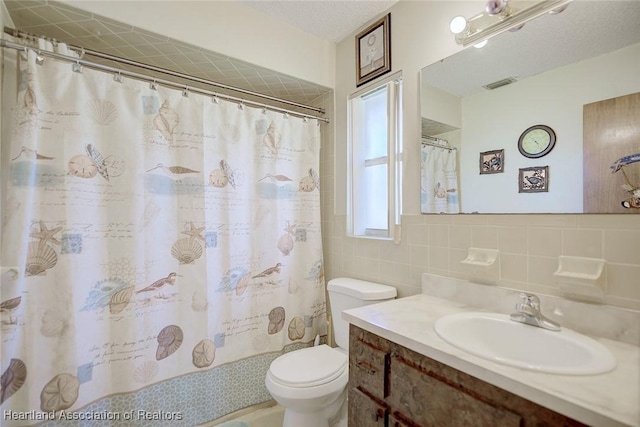 bathroom with tile walls, visible vents, toilet, a textured ceiling, and vanity