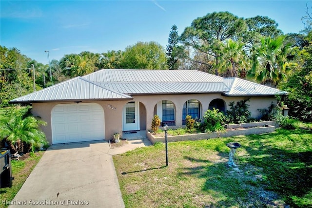 view of front of home featuring metal roof, a garage, concrete driveway, stucco siding, and a front yard