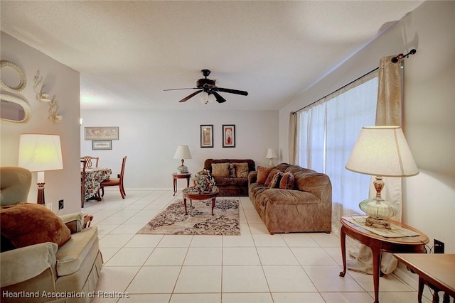 living area featuring light tile patterned floors, a textured ceiling, baseboards, and a ceiling fan