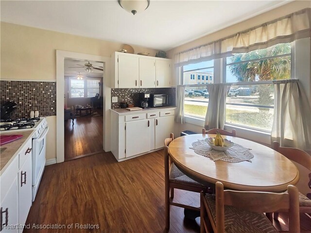 21 N French Ave, Fort Meade, FL 33841 - kitchen with white gas stove, white cabinets, backsplash, and dark wood-type flooring