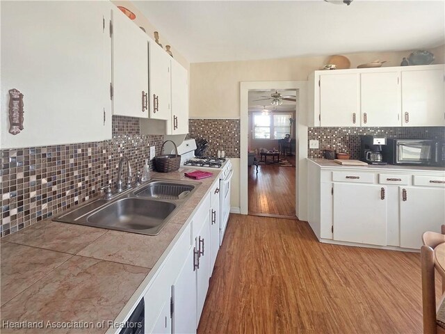 21 N French Ave, Fort Meade, FL 33841 - kitchen with a sink, black microwave, light wood-type flooring, white cabinets, and ceiling fan