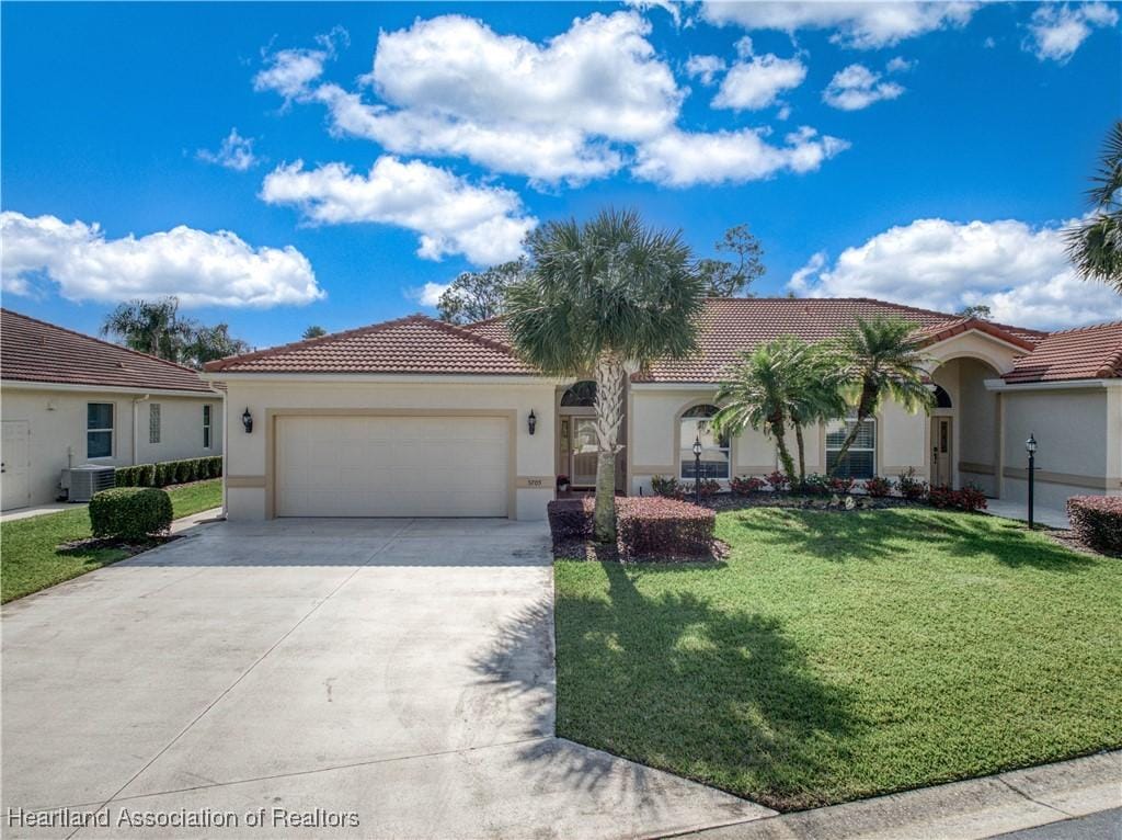 mediterranean / spanish-style house featuring a front yard, a garage, and central AC unit