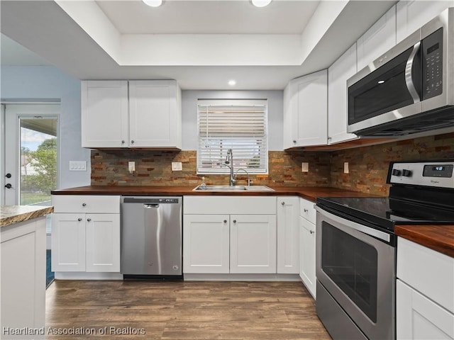 kitchen with a raised ceiling, sink, white cabinetry, and stainless steel appliances