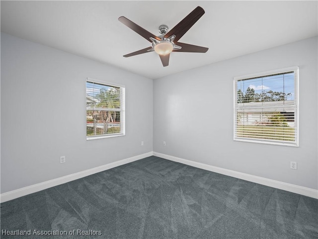 spare room with ceiling fan and dark carpet