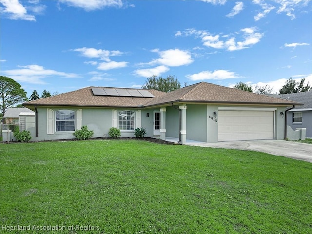 ranch-style home with solar panels, a garage, and a front yard