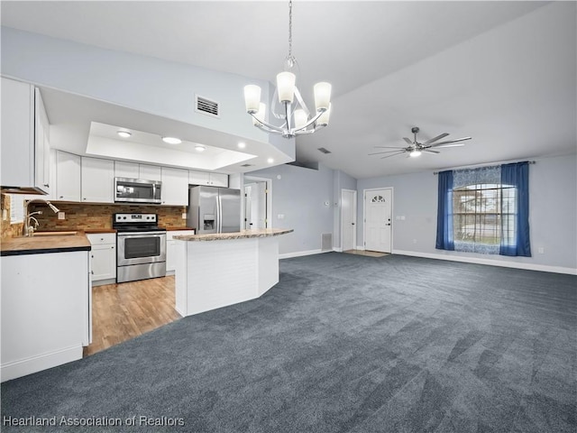 kitchen featuring appliances with stainless steel finishes, ceiling fan with notable chandelier, sink, pendant lighting, and white cabinetry