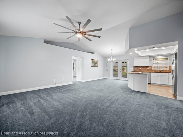 unfurnished living room featuring lofted ceiling, sink, light colored carpet, and ceiling fan with notable chandelier