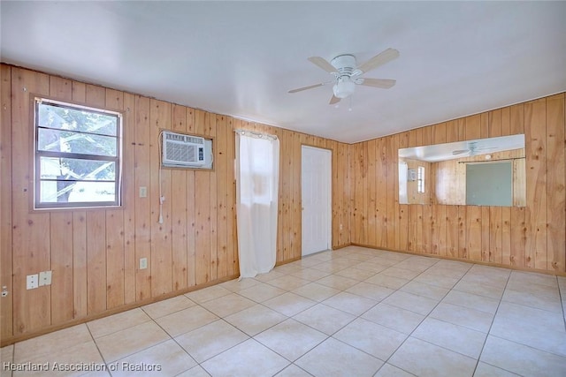 empty room featuring wood walls, a wall mounted air conditioner, light tile patterned floors, baseboards, and ceiling fan
