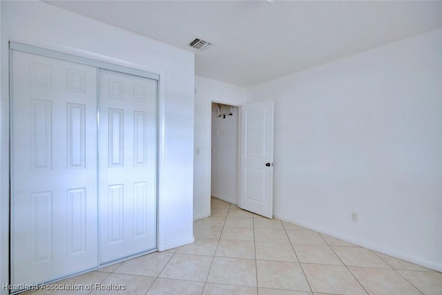 unfurnished bedroom with a closet, visible vents, and light tile patterned floors