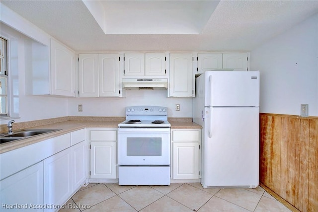 kitchen featuring white appliances, white cabinetry, under cabinet range hood, and a sink
