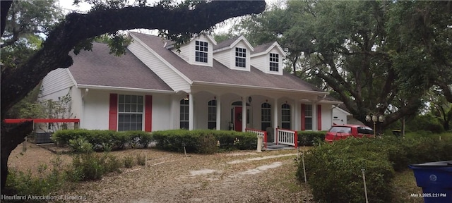 2212 Wolf Rd, Sebring, FL 33875 - cape cod house featuring covered porch, stucco siding, and roof with shingles