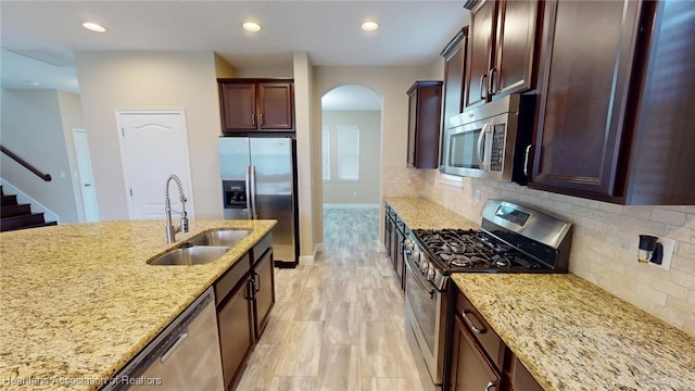 5406 Fishhawk Dr, Lithia, FL 33547 - kitchen with arched walkways, light stone counters, a sink, appliances with stainless steel finishes, and decorative backsplash
