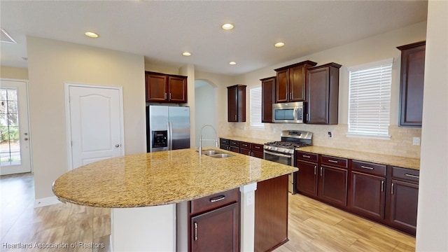 5406 Fishhawk Dr, Lithia, FL 33547 - kitchen with decorative backsplash, an island with sink, appliances with stainless steel finishes, light stone countertops, and a sink