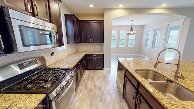 5406 Fishhawk Dr, Lithia, FL 33547 - kitchen with light stone countertops, a sink, hanging light fixtures, appliances with stainless steel finishes, and decorative backsplash