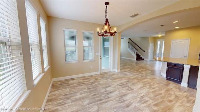 5406 Fishhawk Dr, Lithia, FL 33547 - unfurnished room with baseboards, visible vents, arched walkways, an inviting chandelier, and stairs