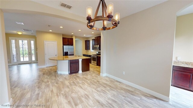 5406 Fishhawk Dr, Lithia, FL 33547 - kitchen featuring appliances with stainless steel finishes, open floor plan, a sink, an island with sink, and light stone countertops