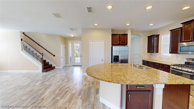 5406 Fishhawk Dr, Lithia, FL 33547 - kitchen featuring a center island with sink, visible vents, light stone counters, stainless steel appliances, and a sink